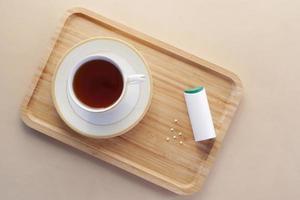 artificial sweetener container and tea cup on table photo