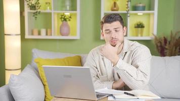 Man looking around thoughtfully thinking about what to write on laptop. Young hardworking man thinks and decides what to do and starts typing on laptop. video