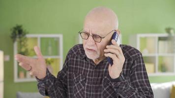 mayor hombre hablando en el teléfono a hogar enojado y agresivo. el antiguo hombre, quien es luchando con el persona en el teléfono, obtiene enojado y gritos a a él. video