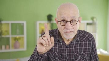 Elderly man looking at camera making be quiet at home sign and warning. Serious and calm old man at home looking at camera making quiet sign and warning, saying no. video