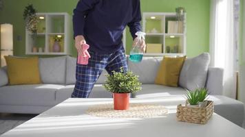 un pensativo y solitario antiguo hombre es limpieza el casa con un plumero, consiguiendo cansado. antiguo hombre limpieza mueble con plumero durante agotador casa limpieza. video