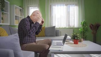 frustrado velho homem trabalhando em computador portátil às lar. frustrado e senil velho homem trabalhando em computador portátil e surpreso de o que ele vê em tela. video