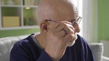 Close-up old man thoughtful and depressed at home. Unhappy retired senior man suffering from loneliness at home, close-up shot of thoughtful serious lonely old man thinking about health problems. video