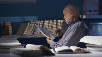 antiguo hombre leyendo un libro en el oscuro habitación. antiguo hombre leyendo un libro, investigador, historiador, alumno, profesor. video