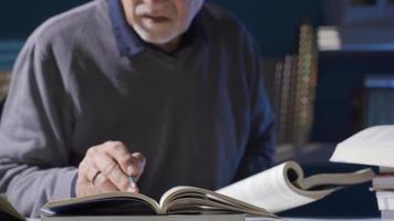 onderzoeker Mens werken met historisch archieven en wetenschappelijk boeken in zijn studie. de ouderen onderzoeker leert nieuw informatie over de onderwerpen hij is onderzoeken in zijn Onderzoek. video