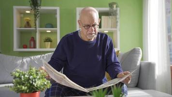 el antiguo hombre es leyendo el periódico a hogar, él es sorprendido por el noticias, él es contento y triste. video