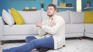 The depressed young man sitting alone on the floor thinks about the events that have happened to him and sighs. Lonely young. video