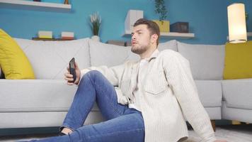 Deprimido hombre cuelga arriba y mira alrededor Deprimido mientras gasto hora en teléfono. mientras el joven hombre es mirando a el teléfono, él pausas para un momento y empieza a Mira alrededor en un infeliz estado. video