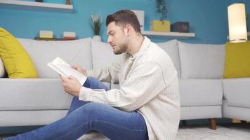 feliz jovem homem lendo uma livro sozinho às lar. a jovem homem é lendo uma livro e é feliz com o que ele lê. video