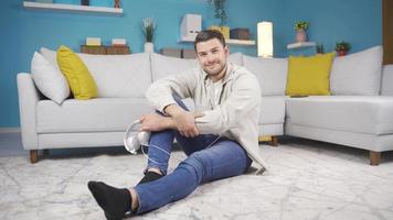 Young man smiling towards the camera. Young man standing on floor in living room smiling looking at camera. video