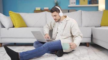 joven hombre utilizando ordenador portátil es infeliz con qué él ve en el pantalla. el hombre hojeada el computadora es muy sorprendido por qué él ve en el pantalla y su estado animico gotas. video