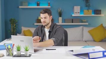 Handsome man laughing looking at camera after getting work done on laptop. Young man using laptop at home, getting things done and looking at camera with a smile. video