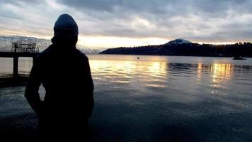 mujer acecho el lago montaña, nublado día puesta de sol video