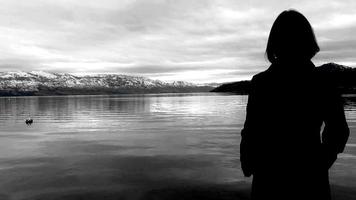 mulher assistindo neve montanha de a lago, nublado inverno dia video