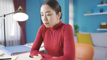 Asian young woman working from home lost in thought about what to do. Cute Asian woman working in home office is thoughtful about what to do while at work. video