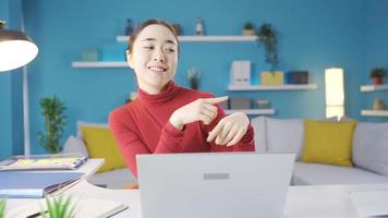 Happy Asian woman starts dancing at the table. Happy young Asian woman sitting at her desk at home says dance. video