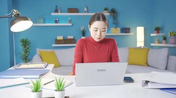 giovane asiatico donna guardare focalizzata a il computer portatile a casa. bellissimo asiatico donna guardare a il computer portatile focalizzata e serio. video