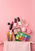 Bright summer eyeshadow palette and makeup products in pink cosmetic bag on pink background photo