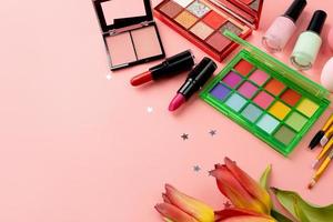 Bright summer eyeshadow palette and makeup products on pink background, vivid summer flatlay photo