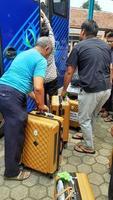 Tangerang Selatan Indonesia March 2023 The men are lifting suitcases onto the bus at the umrah departure ceremony to the holy land of Mecca. photo