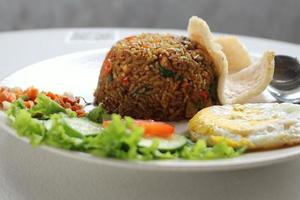 indonesio frito arroz nasi goreng servido con soja salsa, chile pegar sambal, soleado lado arriba y kerupuk galletas foto