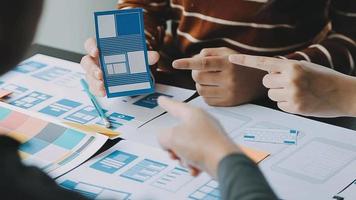 Close up ux developer and ui designer brainstorming about mobile app interface wireframe design on table with customer breif and color code at modern office.Creative digital development agency video