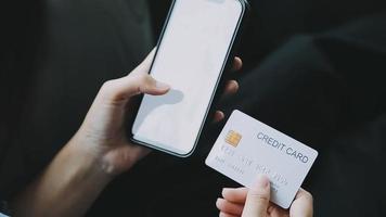 Close up smiling millennial woman holding smartphone and banking credit card, involved in online mobile shopping at home, happy female shopper purchasing goods or services in internet store. video