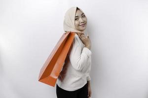 Asian Muslim woman happy beautiful young standing excited holding a shopping bag, studio shot isolated on white background photo