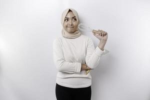 Excited Asian Muslim woman wearing a headscarf, holding cooking ware and smiling, isolated by white background photo