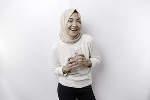 alegre asiático musulmán mujer vistiendo Pañuelo es Bebiendo un vaso de agua, aislado en blanco antecedentes. foto