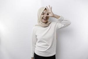 A smiling Asian Muslim woman, giving an OK hand gesture isolated over white background photo