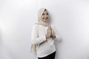 Portrait of a young beautiful Asian Muslim woman wearing a headscarf gesturing Eid Mubarak greeting photo