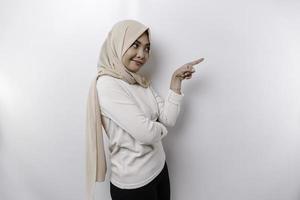 joven asiático musulmán mujer sonriente mientras señalando a Copiar espacio junto a su foto