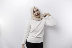 A portrait of a cute Asian Muslim woman wearing a headscarf, and feeling excited and isolated by a white background photo