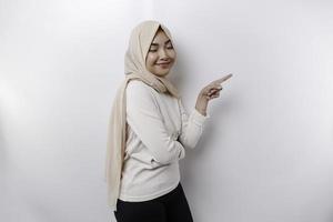 joven asiático musulmán mujer sonriente mientras señalando a Copiar espacio junto a su foto