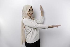 Young Asian Muslim woman smiling while pointing to copy space beside her photo