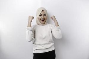 A young Asian Muslim woman with a happy successful expression wearing a hijab isolated by white background photo