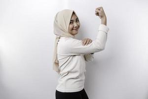 emocionado asiático musulmán mujer vistiendo un Pañuelo demostración fuerte gesto por levantamiento su brazos y músculos sonriente con orgullo