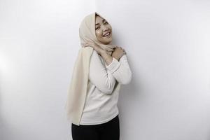 Young beautiful Asian Muslim woman wearing a headscarf over white background hugging herself happy and positive, smiling confident. Self-love and self-care photo