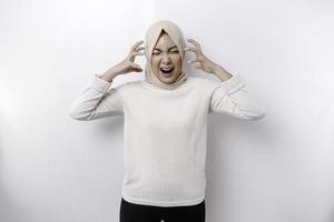 A portrait of an Asian Muslim woman wearing a headscarf isolated by white background looks depressed photo