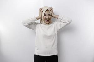 A portrait of an Asian Muslim woman wearing a headscarf isolated by white background looks depressed photo