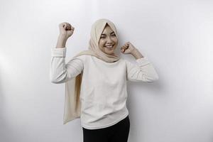 A young Asian Muslim woman with a happy successful expression wearing a hijab isolated by white background photo
