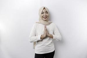 Portrait of a young beautiful Asian Muslim woman wearing a headscarf gesturing Eid Mubarak greeting photo