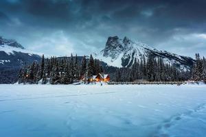 Emerald Lake with wooden lodge glowing in snowy pine forest and rocky mountains on winter at Yoho national park photo