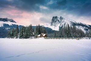 Emerald Lake with wooden lodge glowing in snowy pine forest and rocky mountains on winter at Yoho national park photo