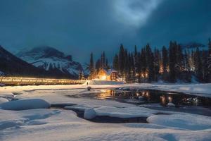 Frozen Emerald Lake with wooden lodge glowing in snowfall on winter at the night photo