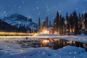 Emerald Lake with wooden lodge glowing and snowfall in pine forest on winter at Yoho national park photo