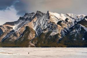 Beautiful frozen Lake Minnewanka with rocky mountains in winter on the evening at Banff national park photo