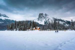 Emerald Lake with wooden lodge glowing in snowy pine forest and rocky mountains on winter at Yoho national park photo