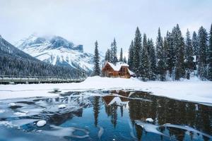 Frozen Emerald Lake with wooden lodge in pine forest on winter photo